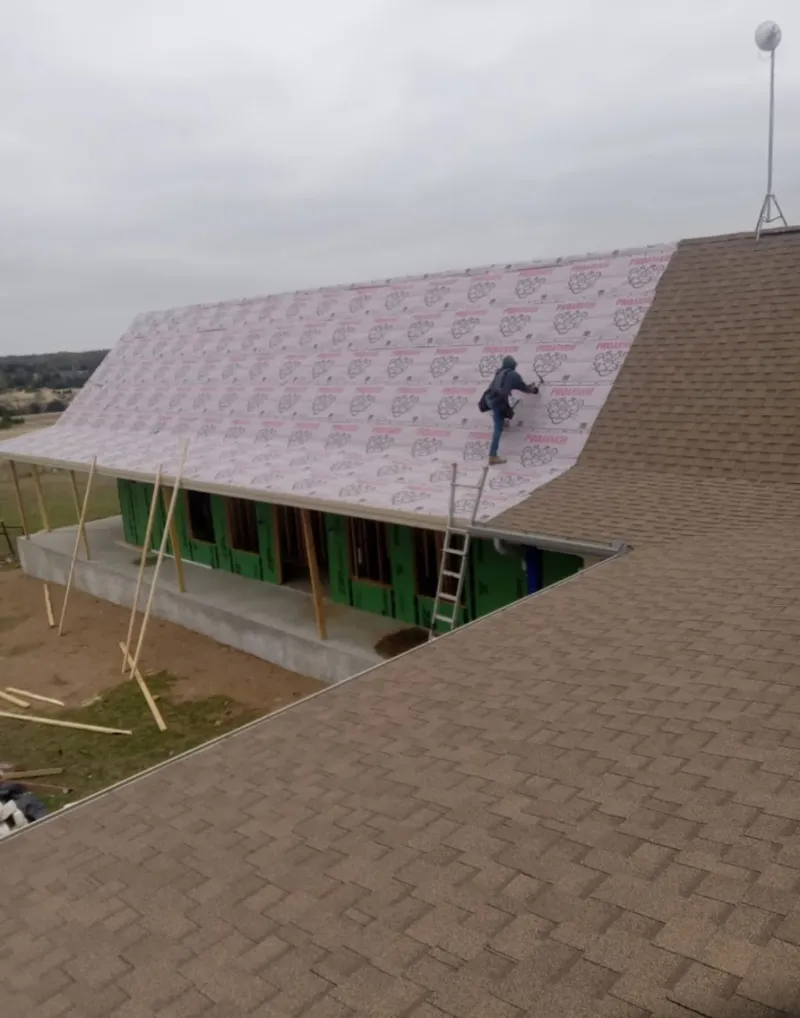 Worker preparing underlayment for a metal roof installation in Smyrna